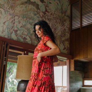 woman with brown hair wearing a flowy maxi tiered dress with retro pink pua print