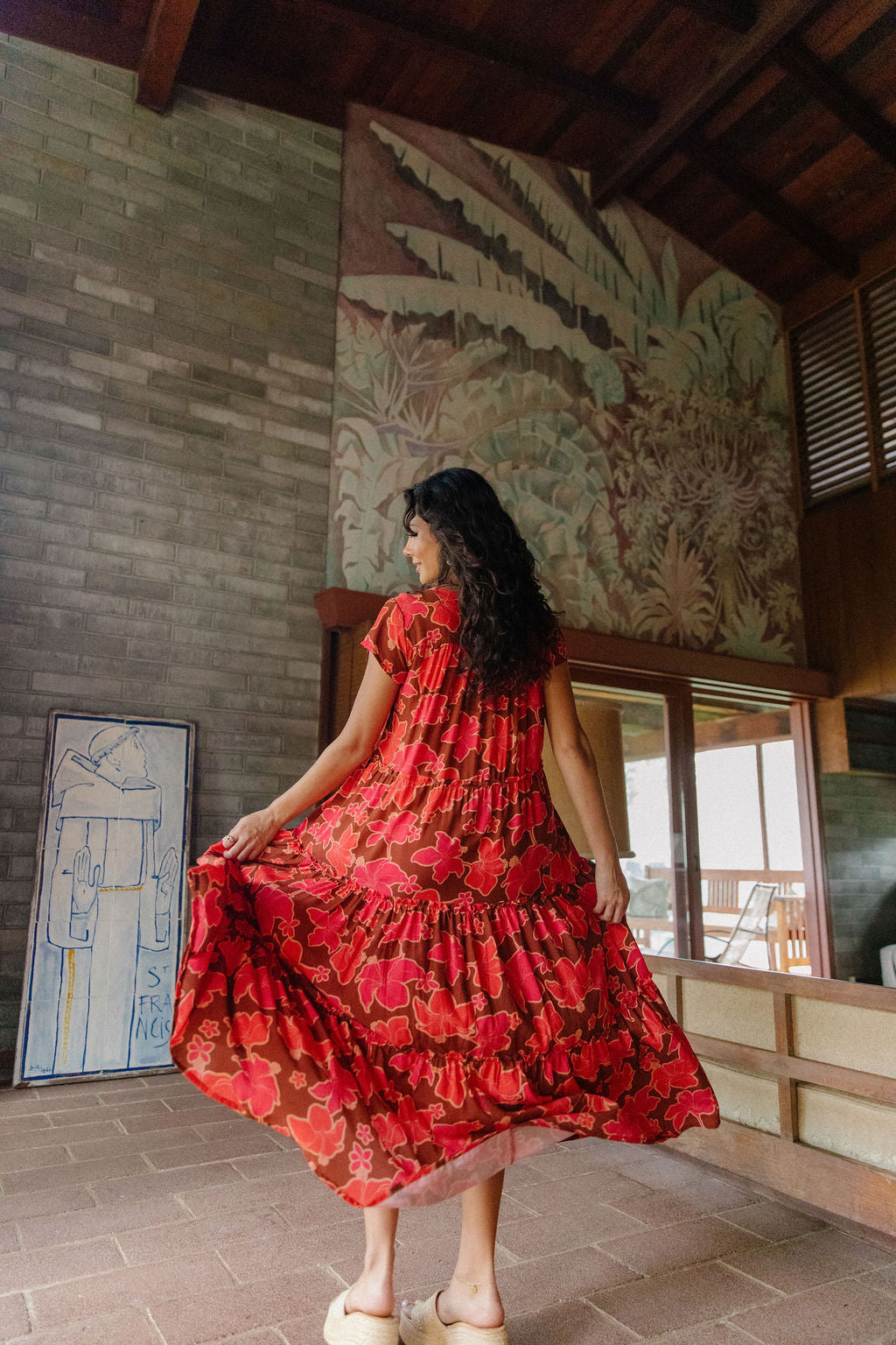 woman with brown hair wearing a flowy maxi tiered dress with retro pink pua print