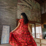 woman with brown hair wearing a flowy maxi tiered dress with retro pink pua print