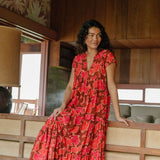 woman with brown hair wearing a flowy maxi tiered dress with retro pink pua print