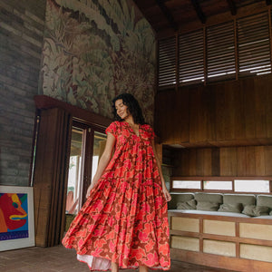 woman with brown hair wearing a flowy maxi tiered dress with retro pink pua print