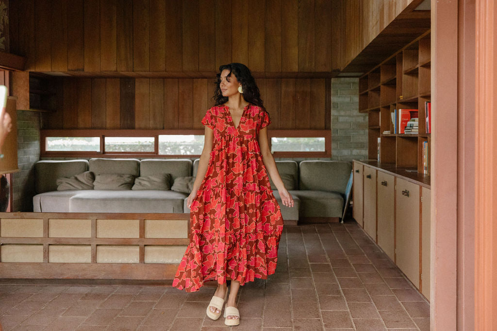 woman with brown hair wearing a flowy maxi tiered dress with retro pink pua print