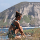 woman with brown hair wearing matching active wear sports bra and shorts set in dark blue floral pattern