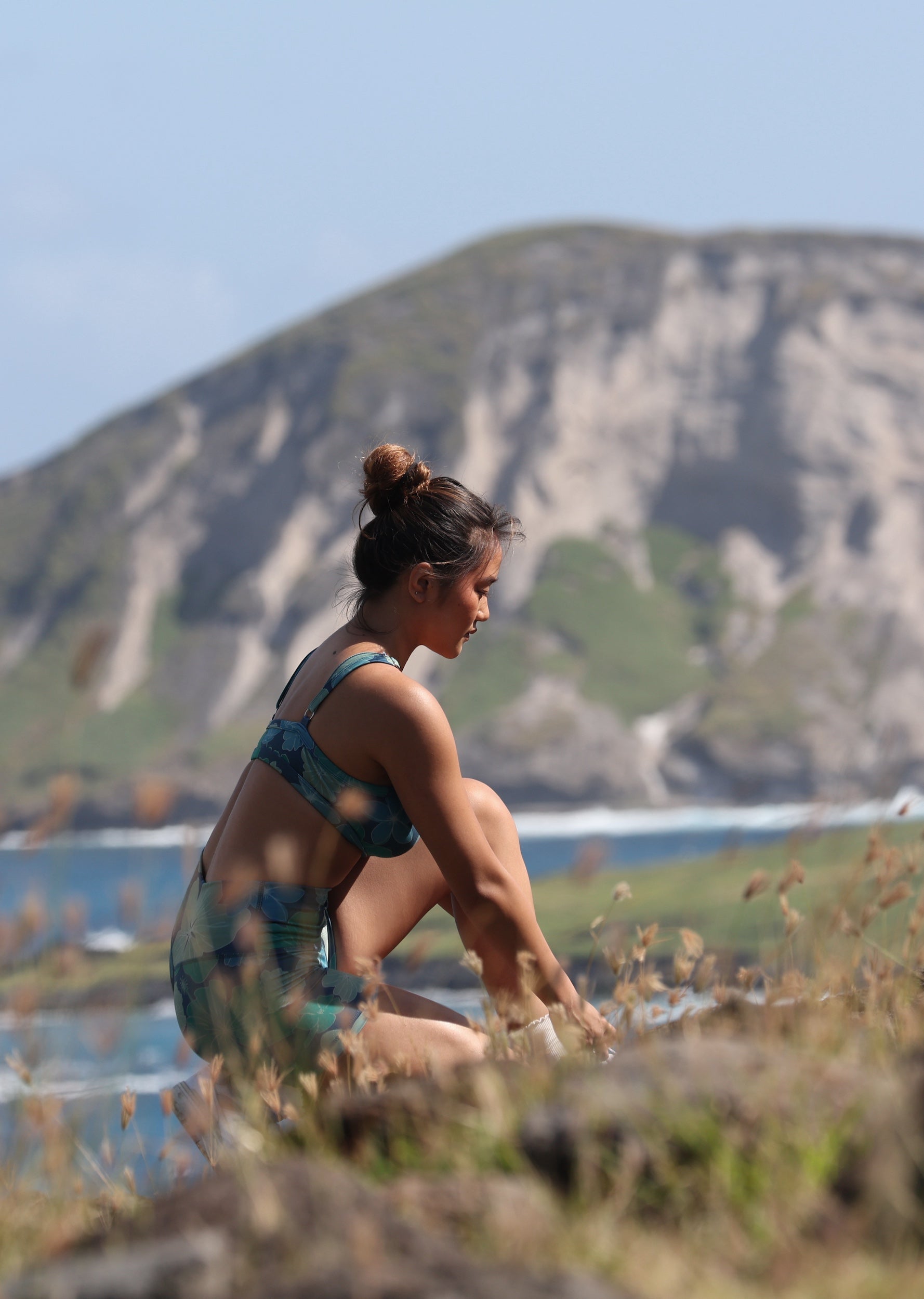 woman with brown hair wearing matching active wear sports bra and shorts set in dark blue floral pattern