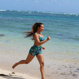 woman with brown hair wearing matching active wear sports bra and shorts set in dark blue floral pattern