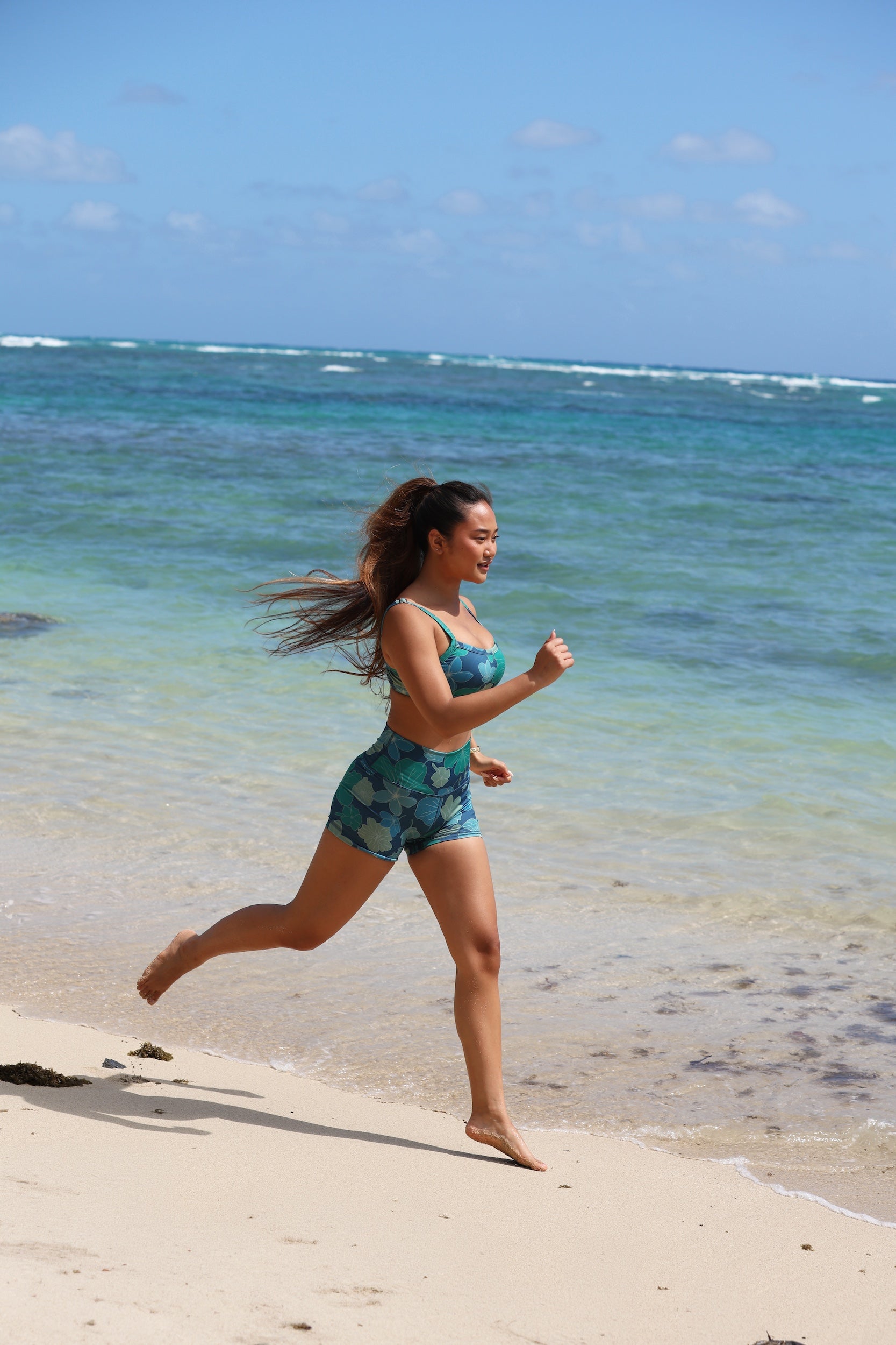 woman with brown hair wearing matching active wear sports bra and shorts set in dark blue floral pattern