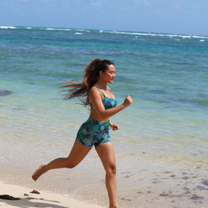 woman with brown hair wearing matching active wear sports bra and shorts set in dark blue floral pattern