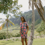 woman with brown hair wearing a navy tailored shirt dress with bright pink hibiscus