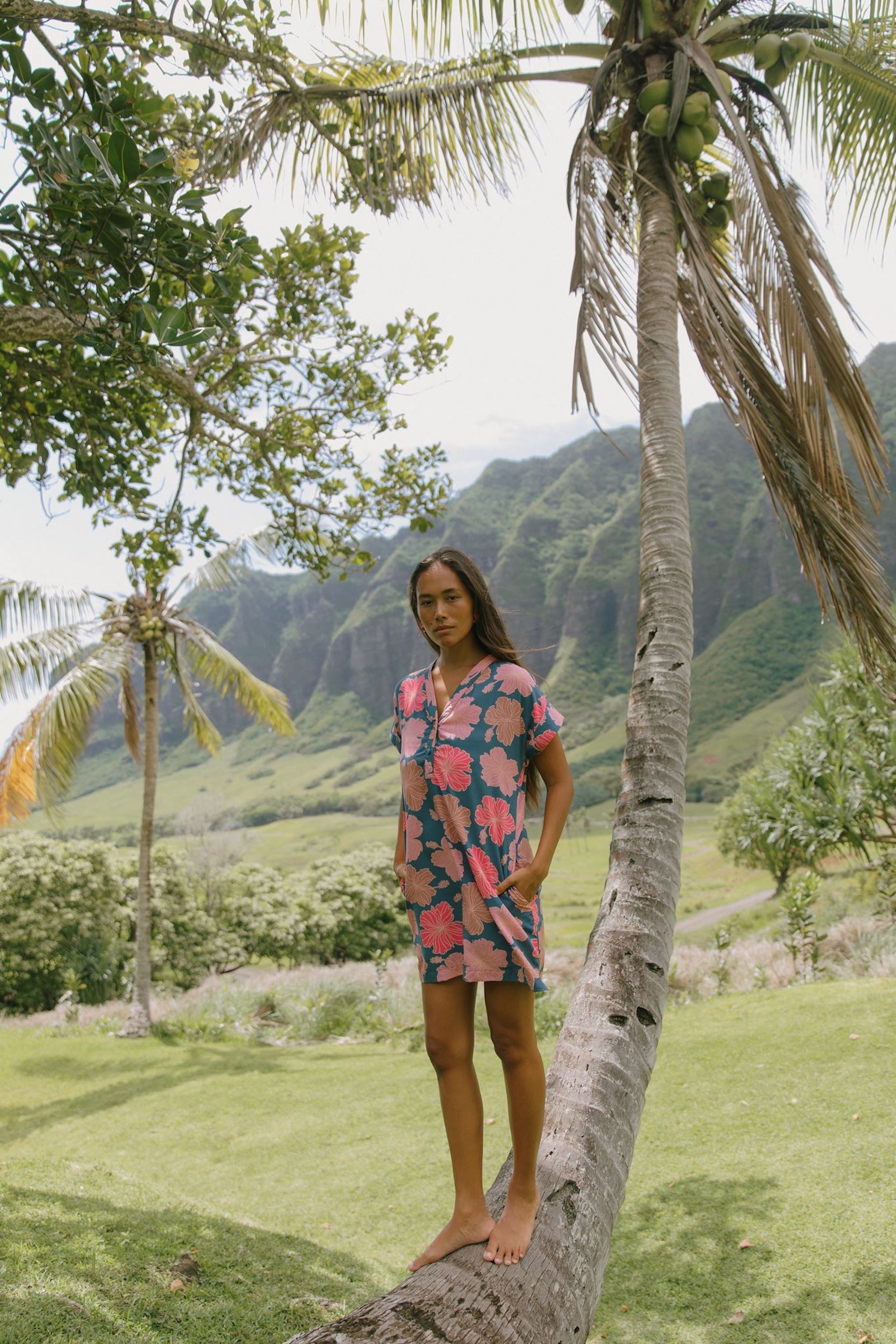 woman with brown hair wearing a navy tailored shirt dress with bright pink hibiscus