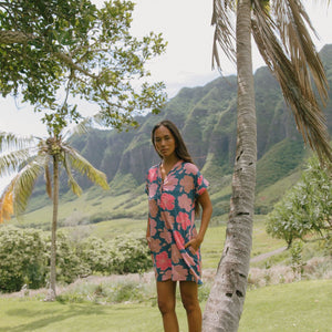 woman with brown hair wearing a navy tailored shirt dress with bright pink hibiscus