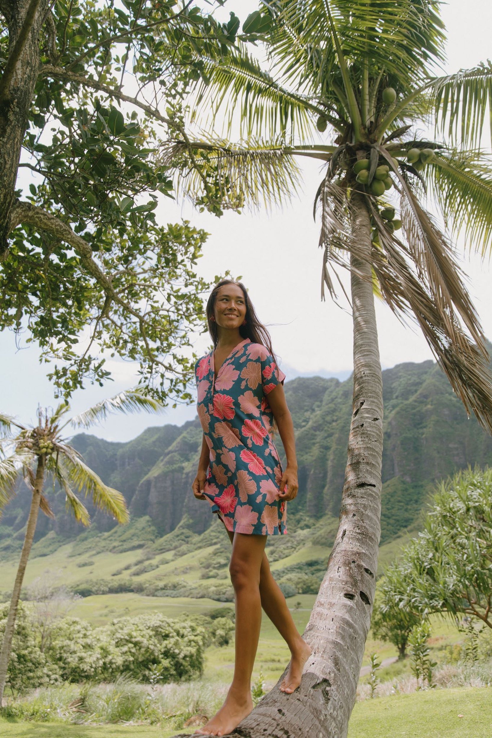 woman with brown hair wearing a navy tailored shirt dress with bright pink hibiscus