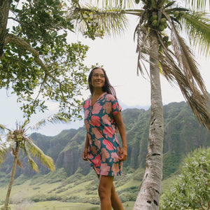 woman with brown hair wearing a navy tailored shirt dress with bright pink hibiscus
