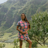 woman with brown hair wearing a navy tailored shirt dress with bright pink hibiscus
