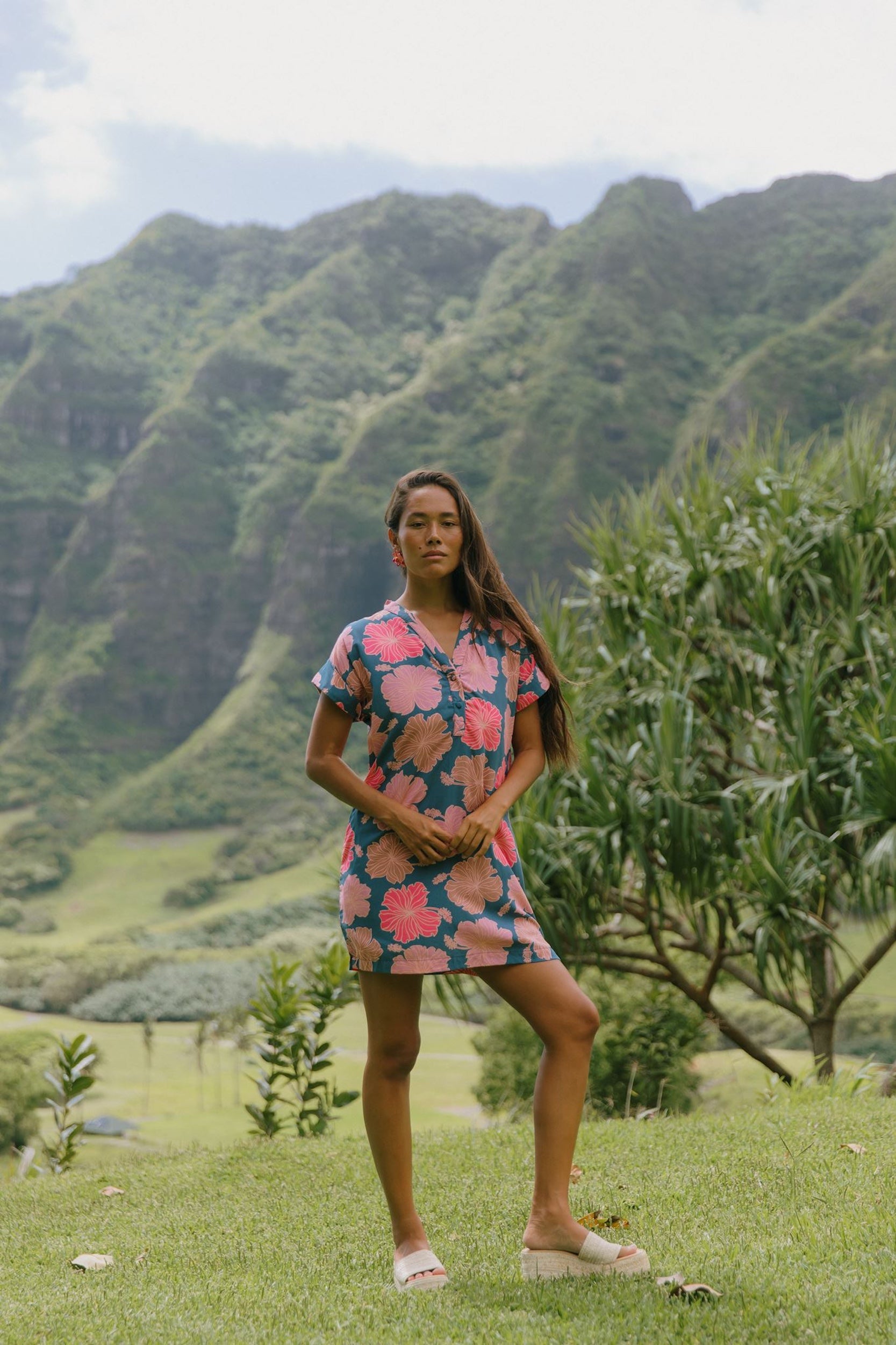 woman with brown hair wearing a navy tailored shirt dress with bright pink hibiscus