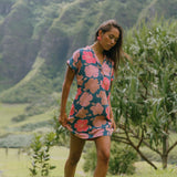 woman with brown hair wearing a navy tailored shirt dress with bright pink hibiscus