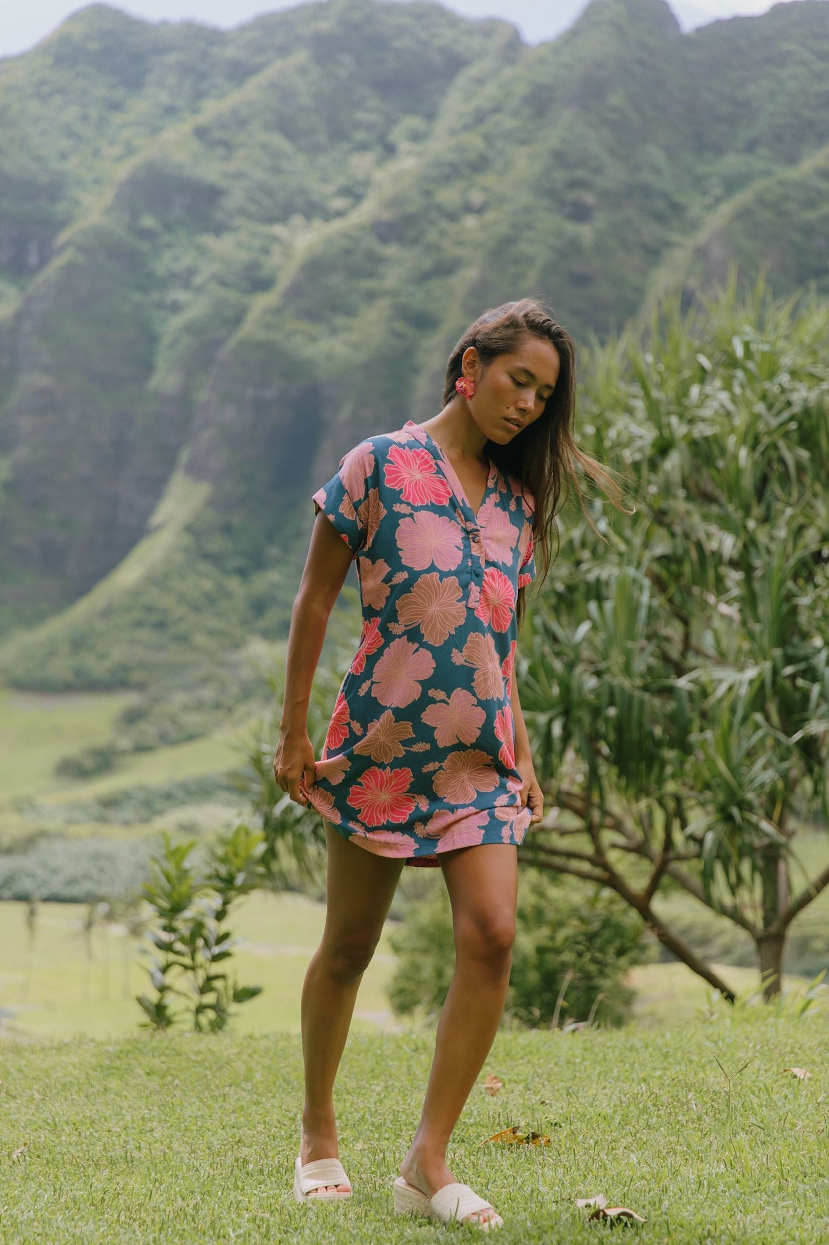 woman with brown hair wearing a navy tailored shirt dress with bright pink hibiscus