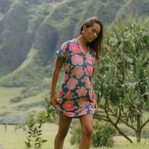 woman with brown hair wearing a navy tailored shirt dress with bright pink hibiscus
