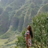 woman with brown hair wearing a navy tailored shirt dress with bright pink hibiscus