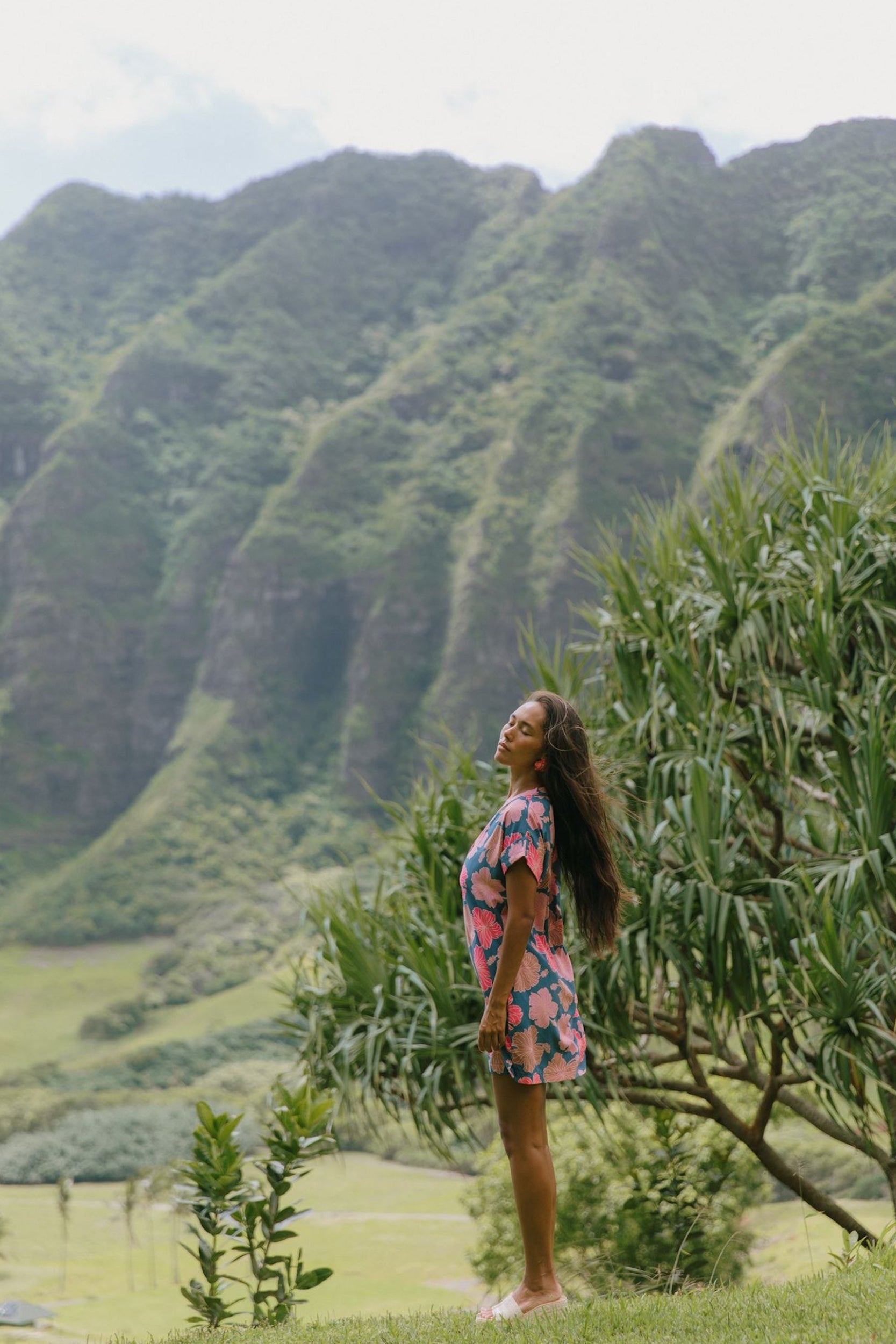 woman with brown hair wearing a navy tailored shirt dress with bright pink hibiscus