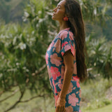 woman with brown hair wearing a navy tailored shirt dress with bright pink hibiscus