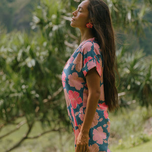 woman with brown hair wearing a navy tailored shirt dress with bright pink hibiscus