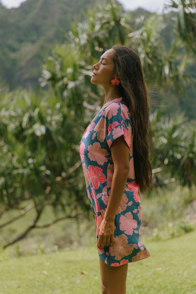 woman with brown hair wearing a navy tailored shirt dress with bright pink hibiscus
