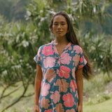 woman with brown hair wearing a navy tailored shirt dress with bright pink hibiscus