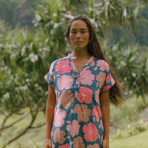 woman with brown hair wearing a navy tailored shirt dress with bright pink hibiscus
