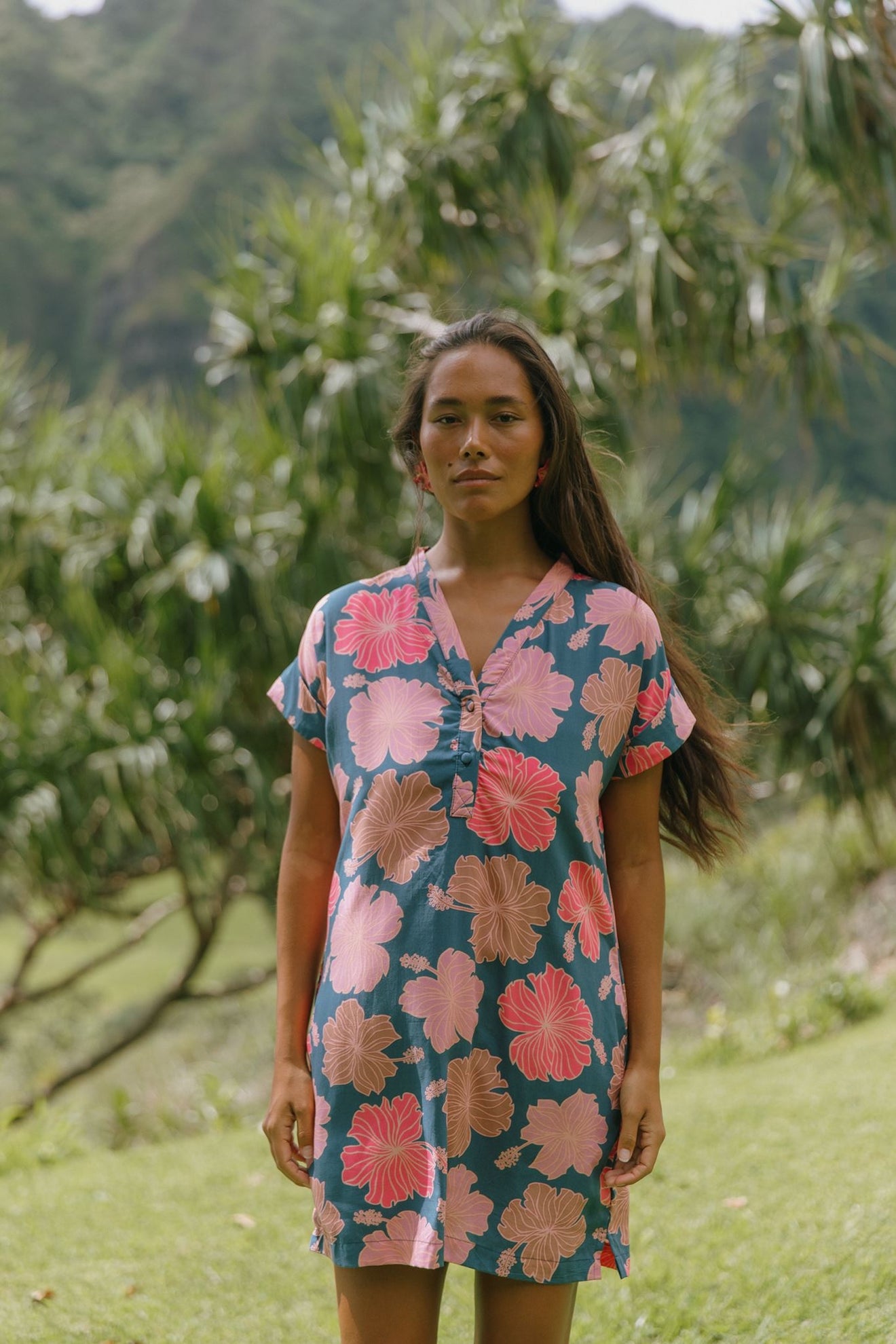 woman with brown hair wearing a navy tailored shirt dress with bright pink hibiscus