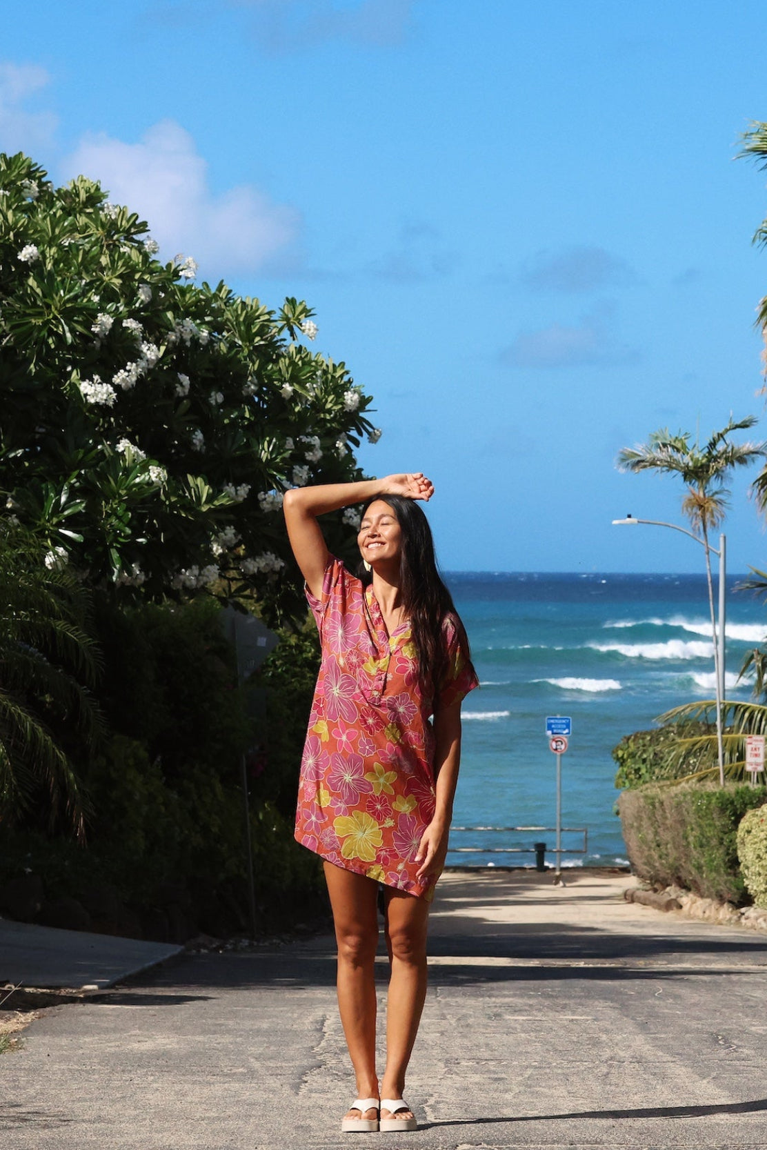 woman with brown hair wearing terracotta colored v neck shirt dress with large purple and yellow flowers