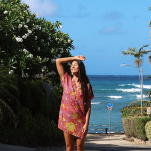 woman with brown hair wearing terracotta colored v neck shirt dress with large purple and yellow flowers
