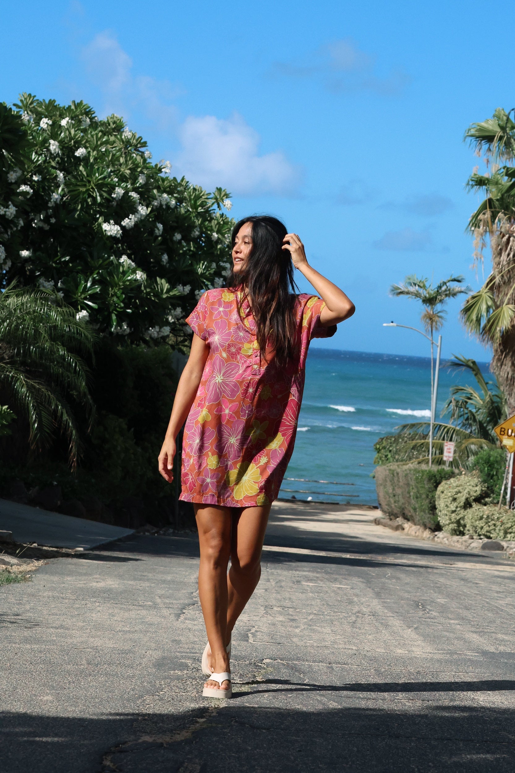 woman with brown hair wearing terracotta colored v neck shirt dress with large purple and yellow flowers