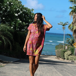 woman with brown hair wearing terracotta colored v neck shirt dress with large purple and yellow flowers