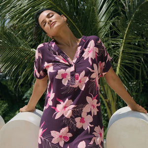 woman with brown hair wearing a dark purple short dress with button up v neck and orchid pattern