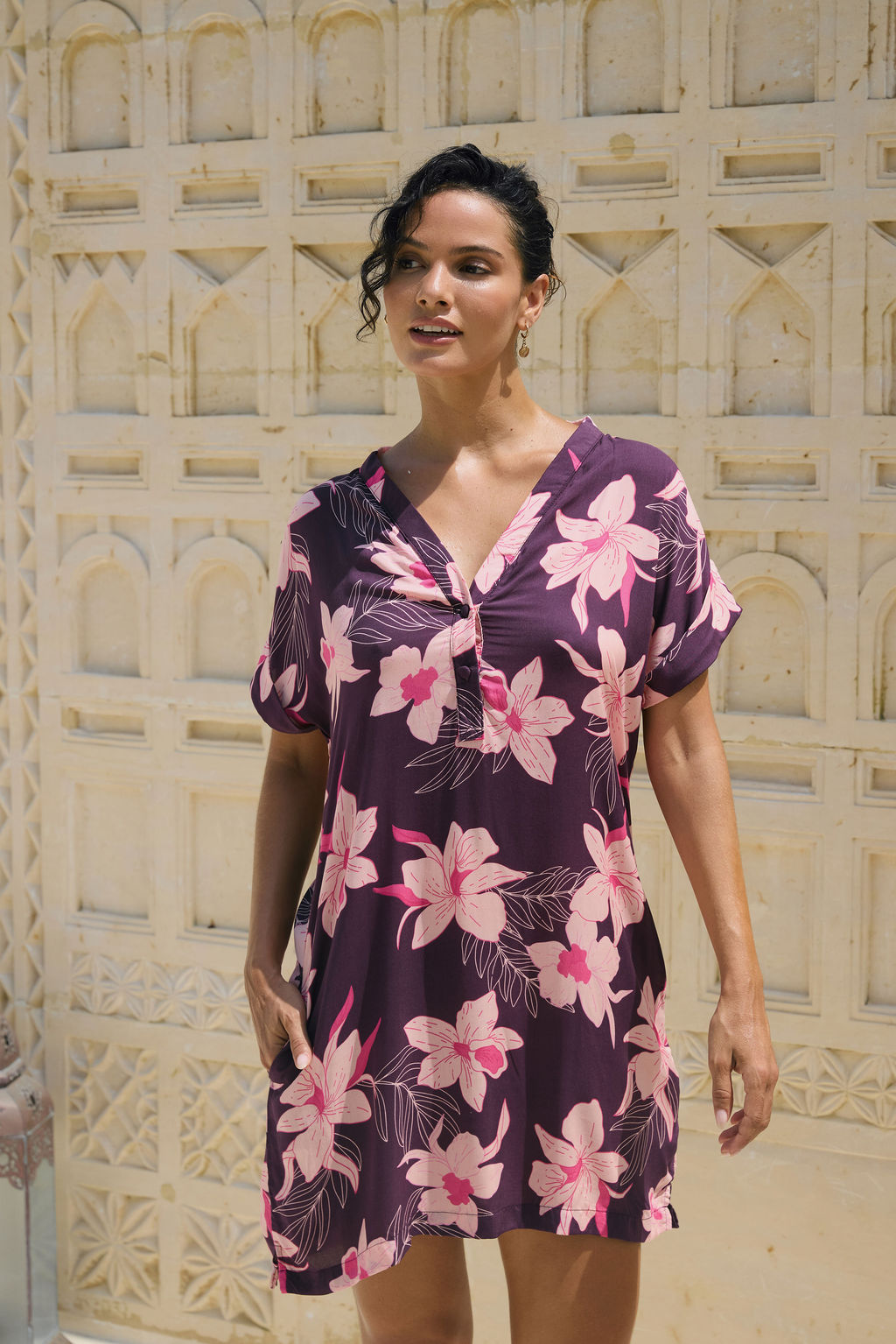 woman with brown hair wearing a dark purple short dress with button up v neck and orchid pattern
