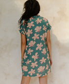 Woman in short sleeve shirt dress with pink floral on teal ground.