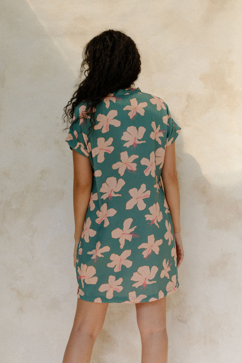 Woman in short sleeve shirt dress with pink floral on teal ground.