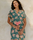 Woman in short sleeve shirt dress with pink floral on teal ground.