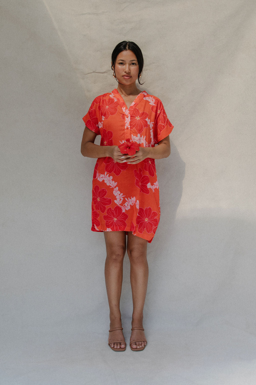 woman with brown hair wearing a retro orange v neck dress with flower pattern
