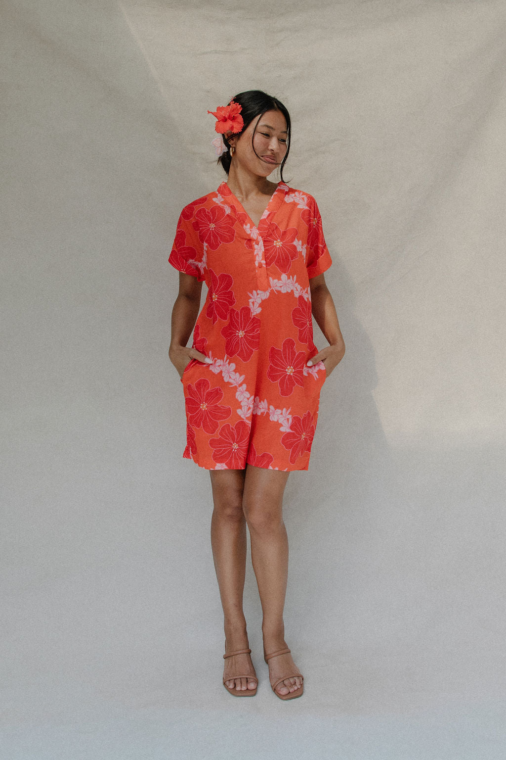 woman with brown hair wearing a retro orange v neck dress with flower pattern