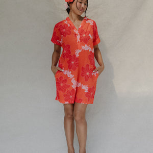 woman with brown hair wearing a retro orange v neck dress with flower pattern