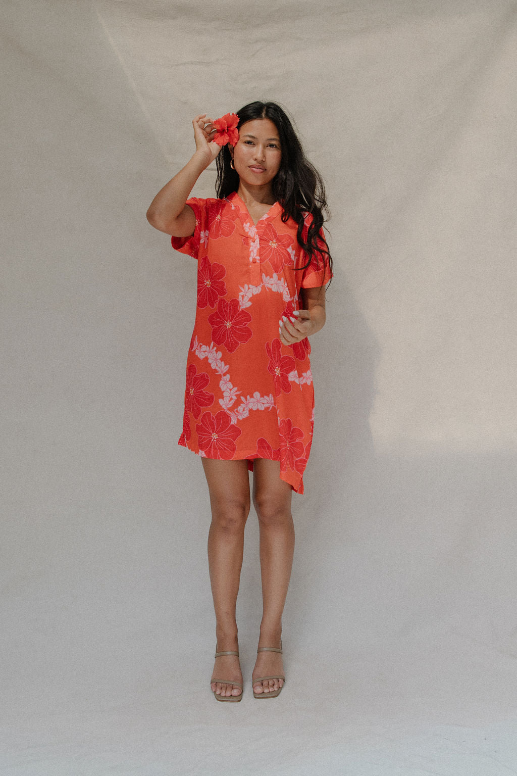woman with brown hair wearing a retro orange v neck dress with flower pattern