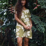 woman with brown hair wearing a shirt dress with v neck in green print with naupaka pattern