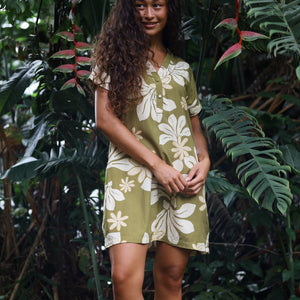 woman with brown hair wearing a shirt dress with v neck in green print with naupaka pattern