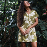 woman with brown hair wearing a shirt dress with v neck in green print with naupaka pattern