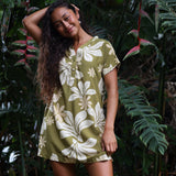 woman with brown hair wearing a shirt dress with v neck in green print with naupaka pattern