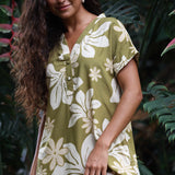 woman with brown hair wearing a shirt dress with v neck in green print with naupaka pattern