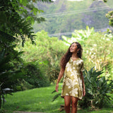 woman with brown hair wearing a shirt dress with v neck in green print with naupaka pattern