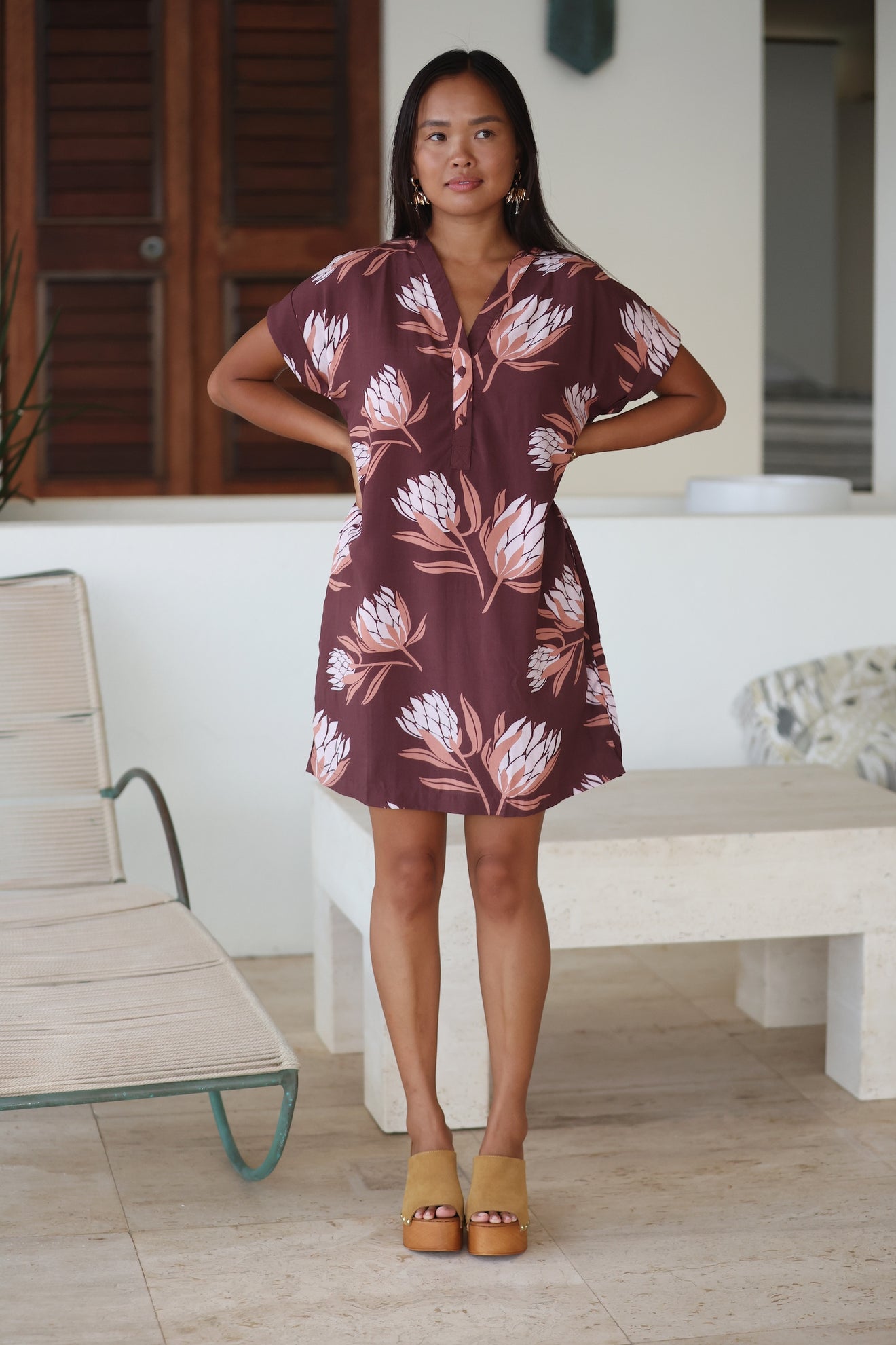 woman wearing a brown knee length v-neck dress with protea pattern