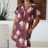 woman wearing a brown knee length v-neck dress with protea pattern